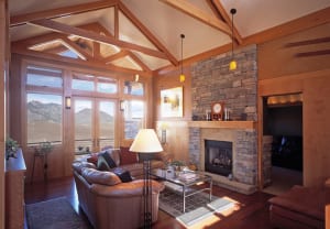 Living room with timber trusses, customwood paneling, and view to foothills