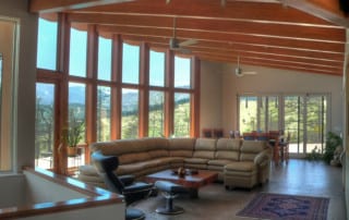 Home rebuilt after wildfire following fire resistant home building standards. Open living room with vaulted ceiling and beams.