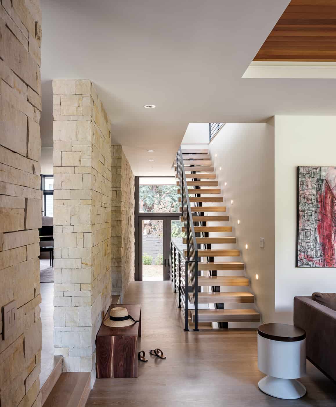 Modern entryway with floating staircase and light stone walls