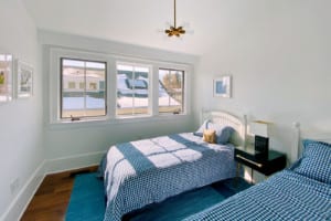 Remodeled kids bedroom with two twin beds and large windows