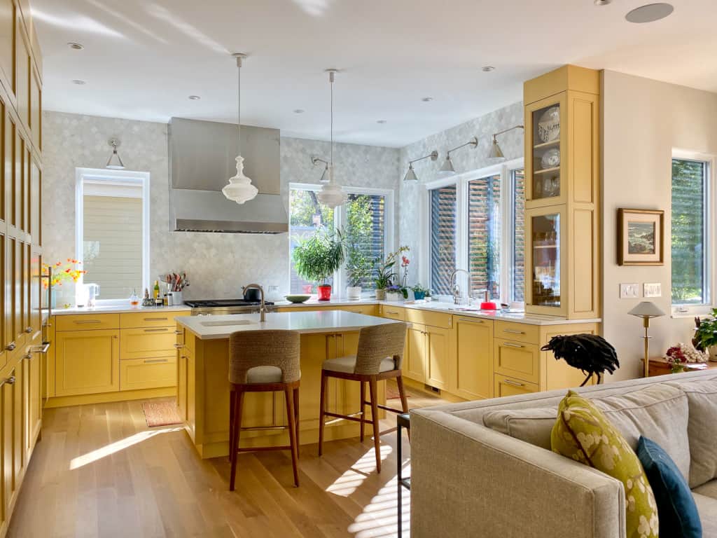 Sunny kitchen remodeled by Cottonwood Custom Builders with yellow cabinets, white quartz counter tops, and tiled walls