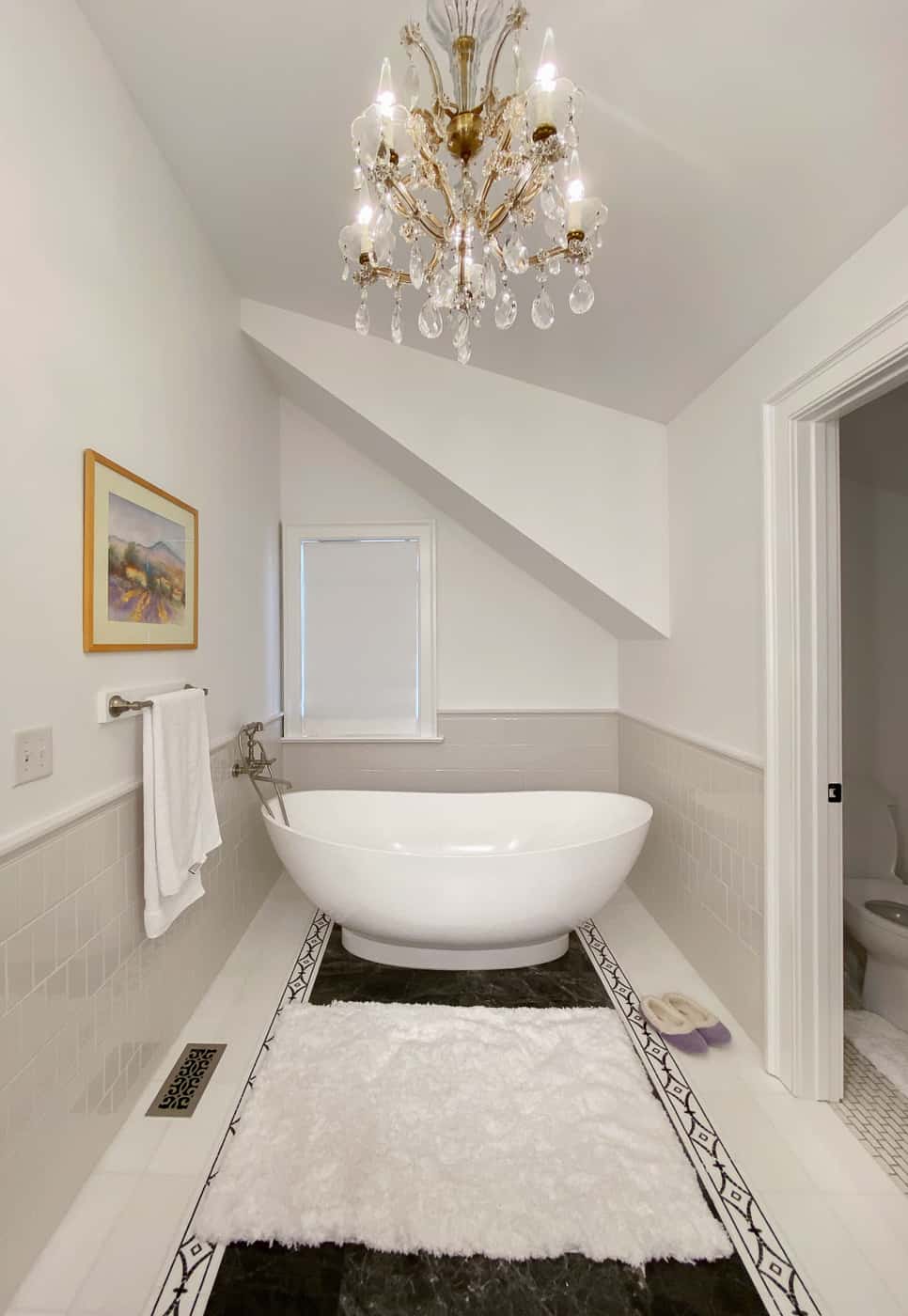 Remodeled master bathroom with slipper tub and custom black and white tile and chandelier